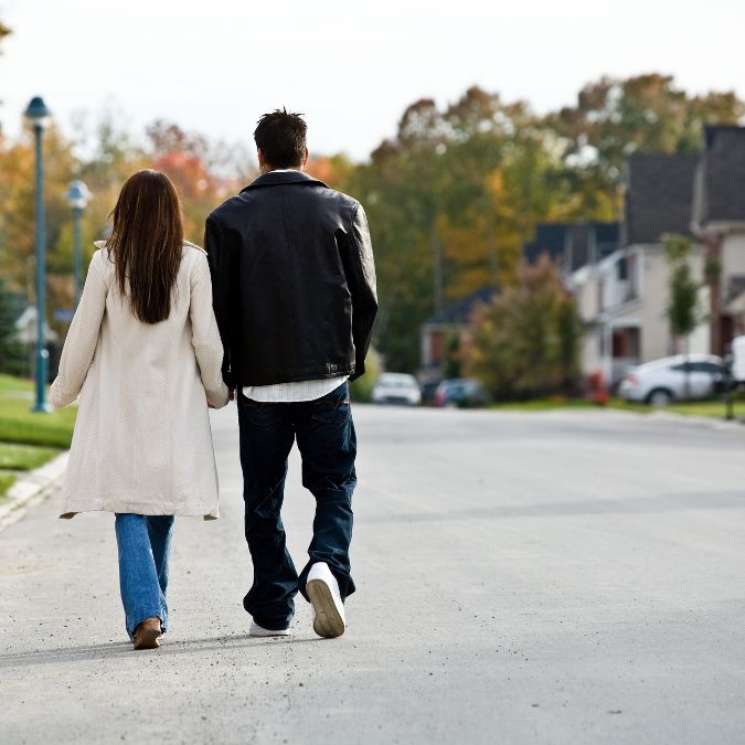 couple holding hands walking through neighborhood