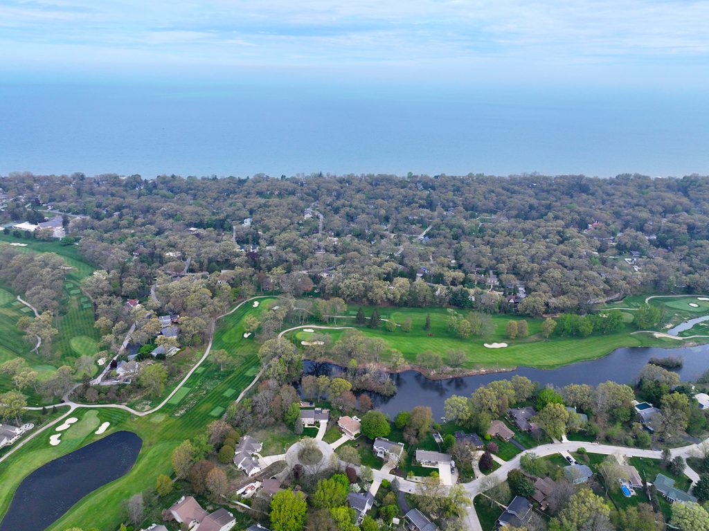 drone shot taken from the site of The Moore development looking out over the beautiful greens of Long Beach Country Club's golf course and the surrounding wooded neighborhoods to a horizon of Lake Michigan